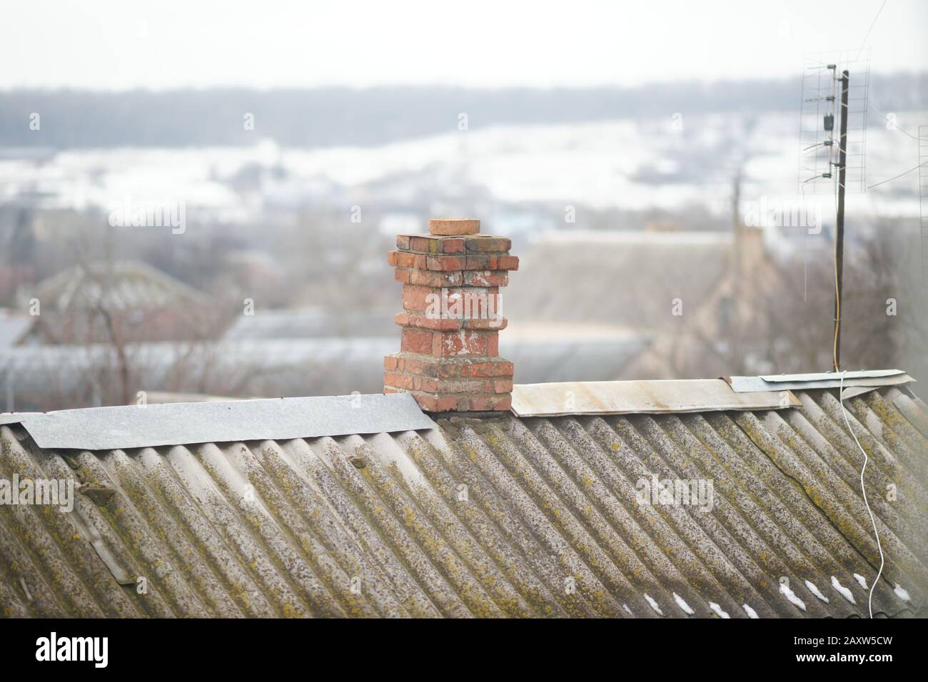 Chimney in red bricks on the old rural roof Stock Photo