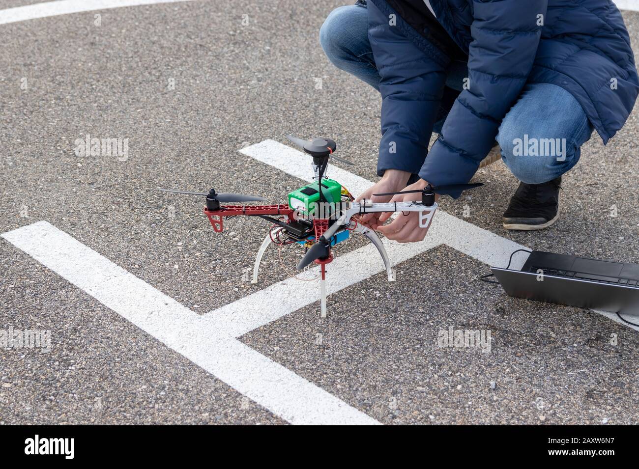 Person preparing a drone for flight. Research UAV and laptop ground station. Stock Photo