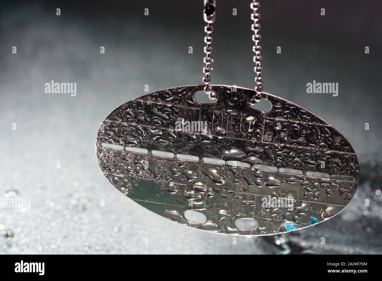 Dog tag with water drops and empty practice ammunition pods photographed in the studio Stock Photo