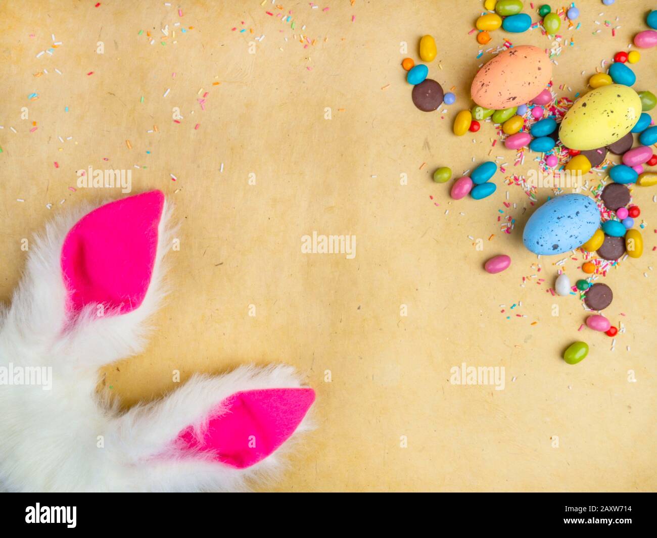 Cute creative composition with multi colored easter eggs, colorful sweets, and bunny ears. Easter and Springtime concept Stock Photo