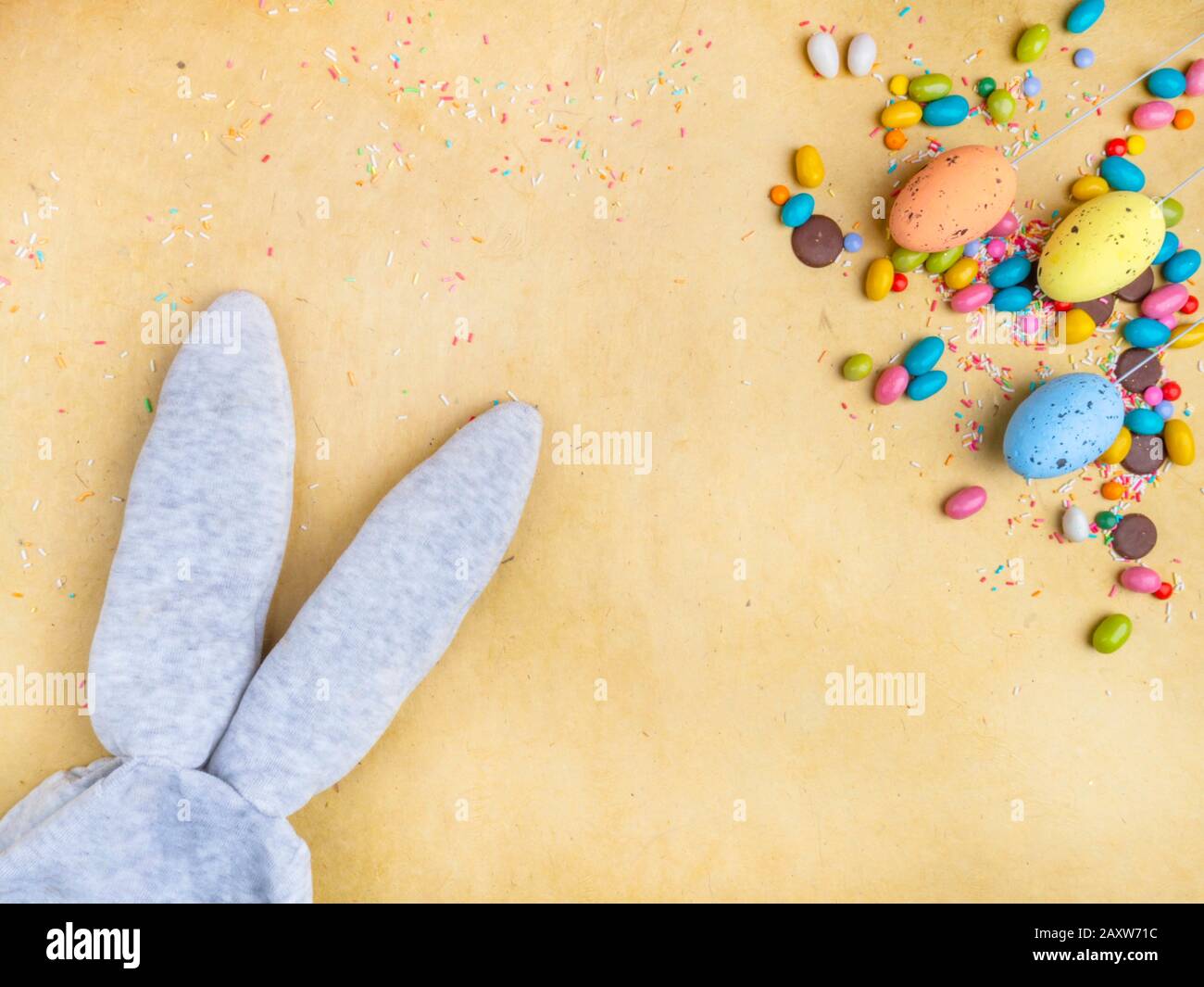 Cute creative composition with multi colored easter eggs, colorful sweets, and bunny ears. Easter and Springtime concept Stock Photo