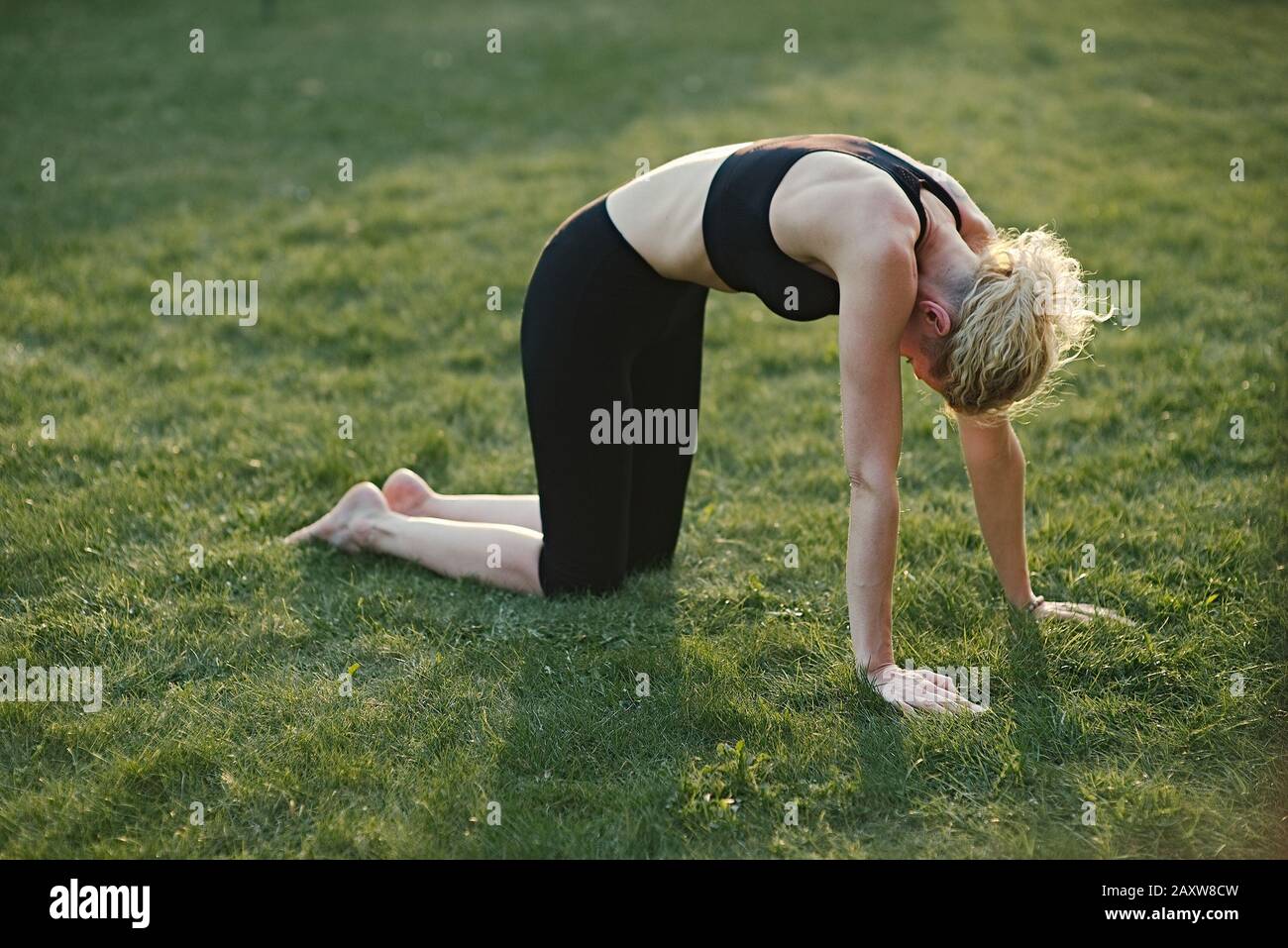 Young woman doing yoga in meditation posture on a mat in the garden. Stock Photo
