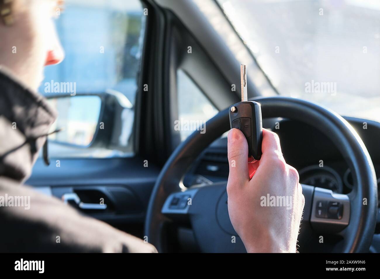 Driving school, a young driver driving a car. Ignition key in hand