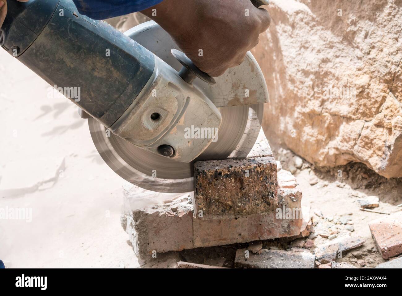 angle grinder, side grinder, disc grinder which is a handheld power tool being used to cut or grind bricks by a worker or operator, close up Stock Photo