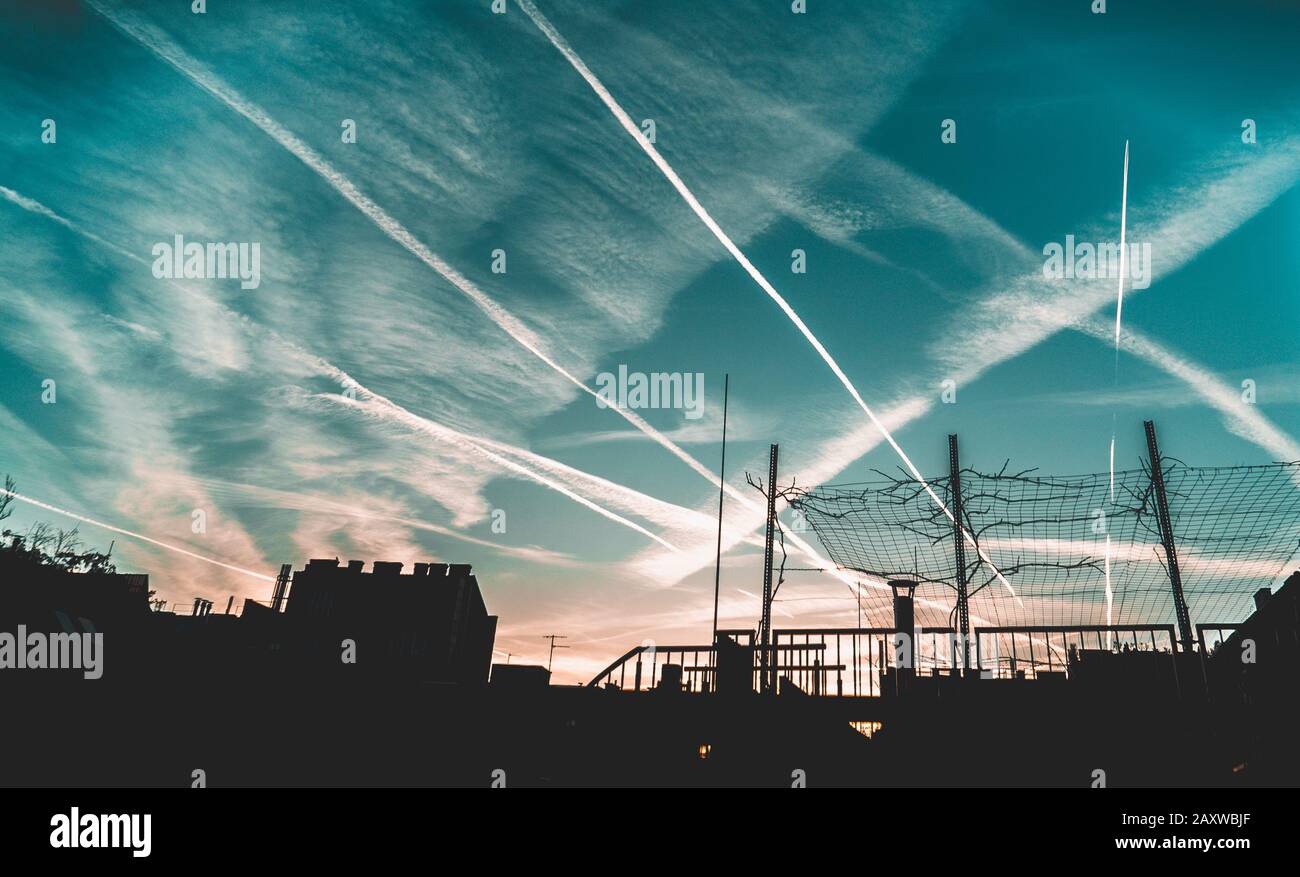 City skyline at sunset with airplane condence trails Stock Photo
