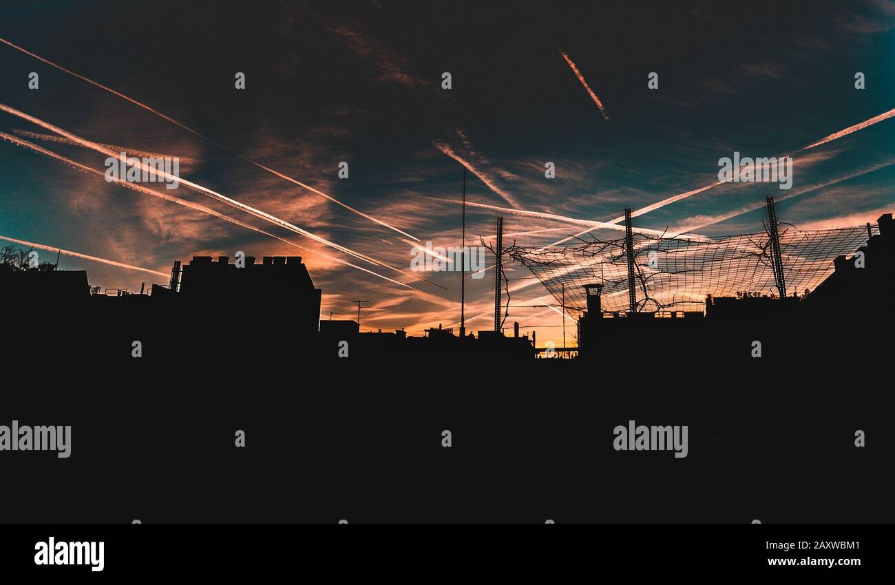 City skyline at sunset with airplane condence trails Stock Photo