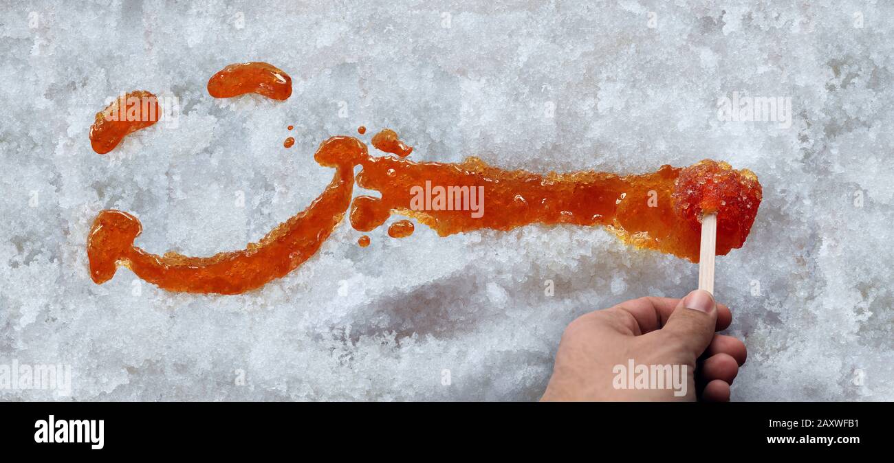 Maple taffy happy face smile as boiled tree sap and sweet boiled syrup on snow as spring food culture from Quebec Ontario Canada and New England. Stock Photo