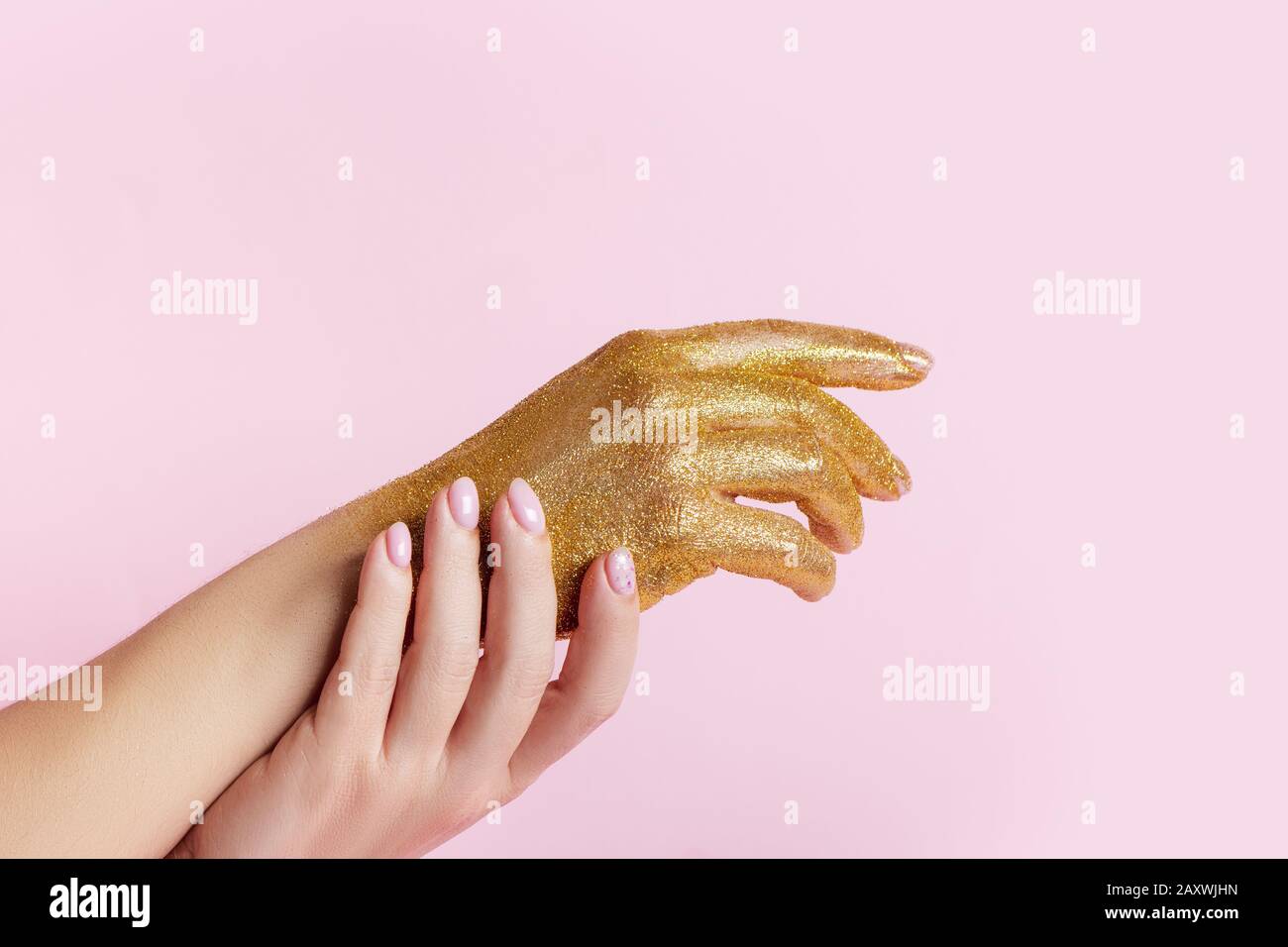 Perfect manicure with trendy nail art and hand with golden glitter on pink background with copy space. Stock Photo