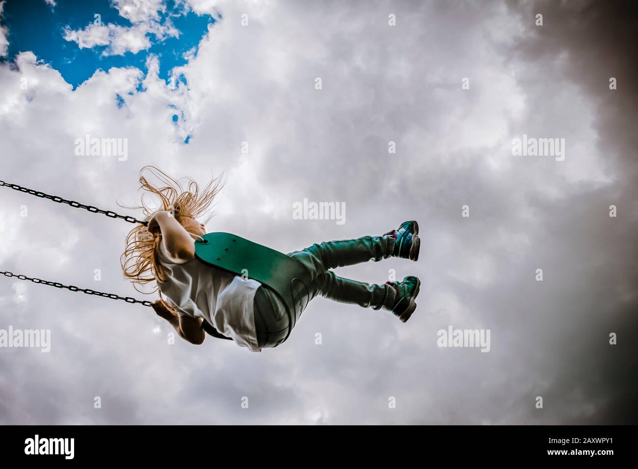 Girl on a swing on a cloudy day Stock Photo
