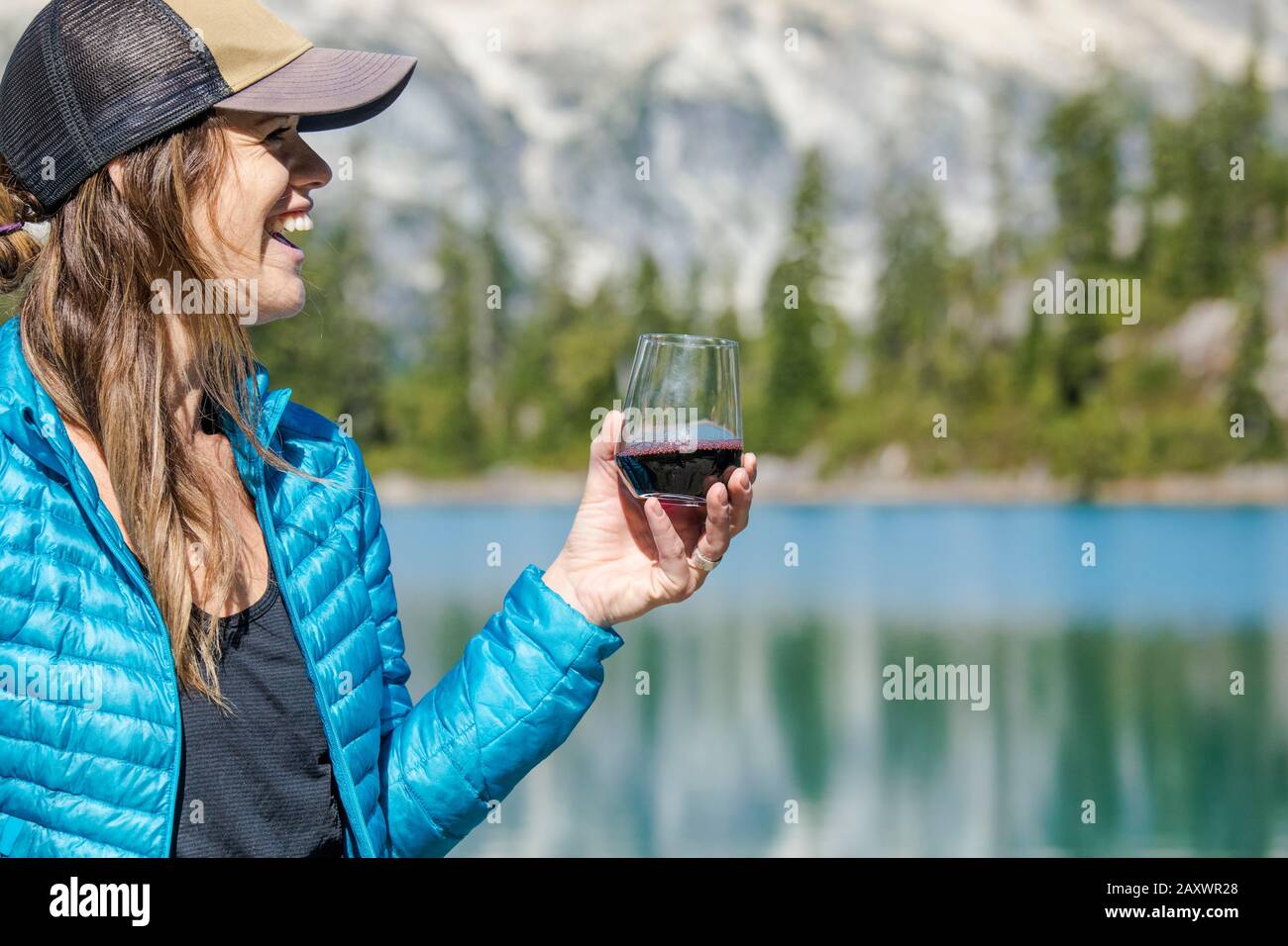 Young active attractive woman enjoys red wine at the lake. Stock Photo