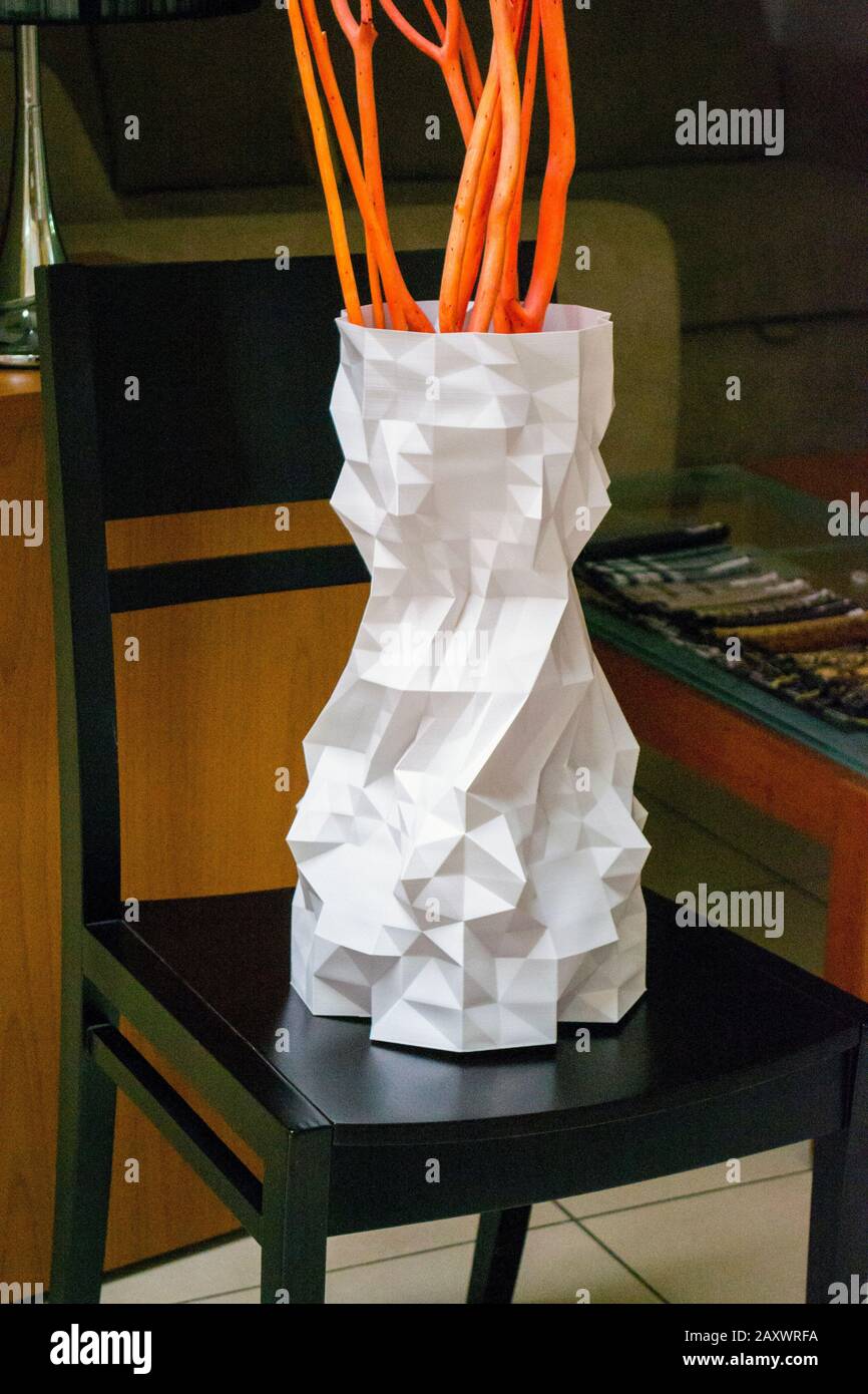 A large vase printed on a 3d printer stands on a chair in an interior ...