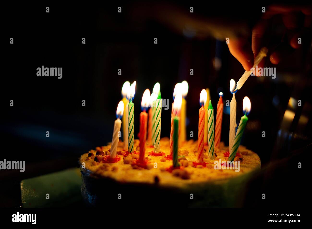 Hand lighting the candles on a birthday cake Stock Photo Alamy