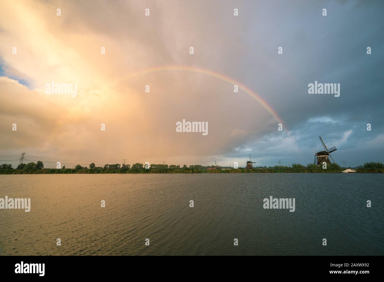 Bright rainbow over a lake with windmill standing at the shore Stock Photo