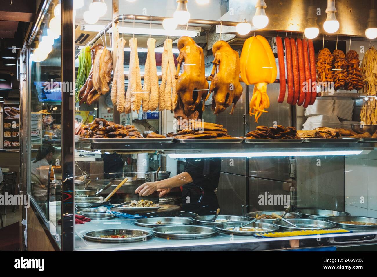 Hong Kong - November, 2019: Chinese restaurant chef preparing food behind shop window Stock Photo