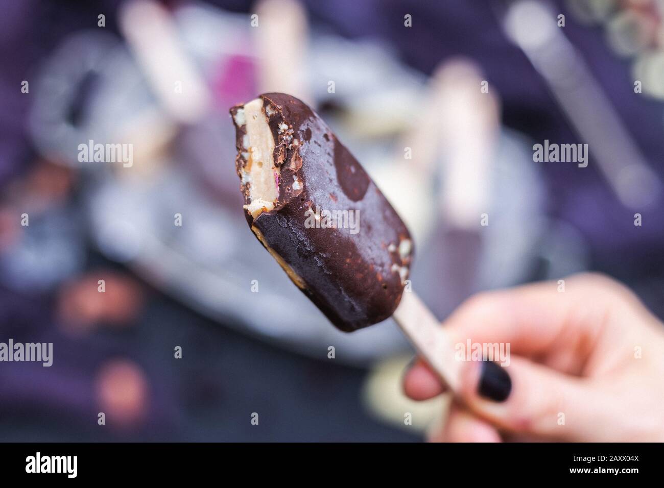 Home-made vegan icecream covered by chocolate in the female hands Stock Photo
