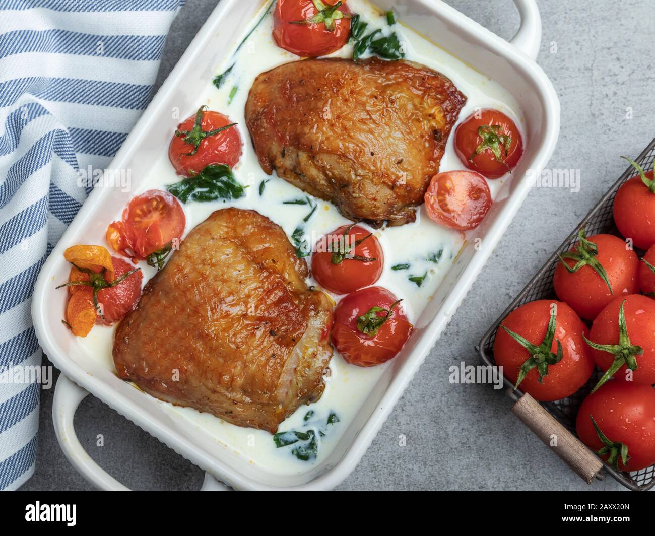 baked chicken thigh with creamy spinach and cherry tomatoes Stock Photo