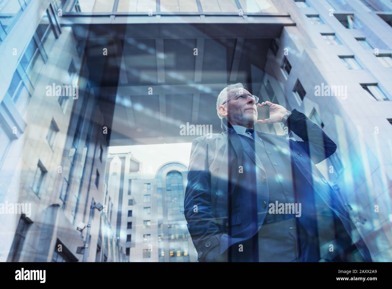 Senior businessman speaks on the mobile while walking in a modern city. Double exposure effect Stock Photo