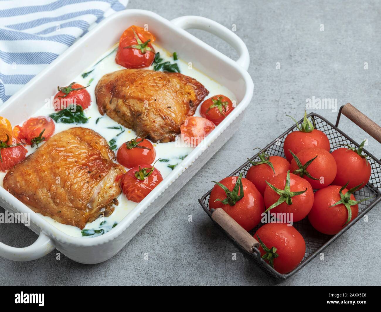 baked chicken thigh with creamy spinach and cherry tomatoes Stock Photo