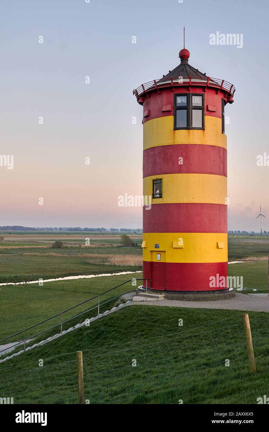 Red and yellow lighthouse on a dyke near Pilsum, LowerSaxony, Germany
