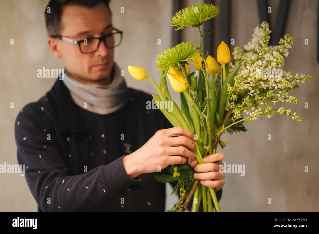 Flowers delivery shop. Florist creating order, making spring bouquet. Male make bouquet using yellow tulips Stock Photo