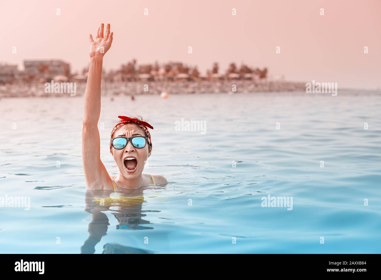 Desperate asian woman swimming in the sea and asking for help, shouts and raises her hand. Concept of accidents and drowning in water, lifeguard on th Stock Photo