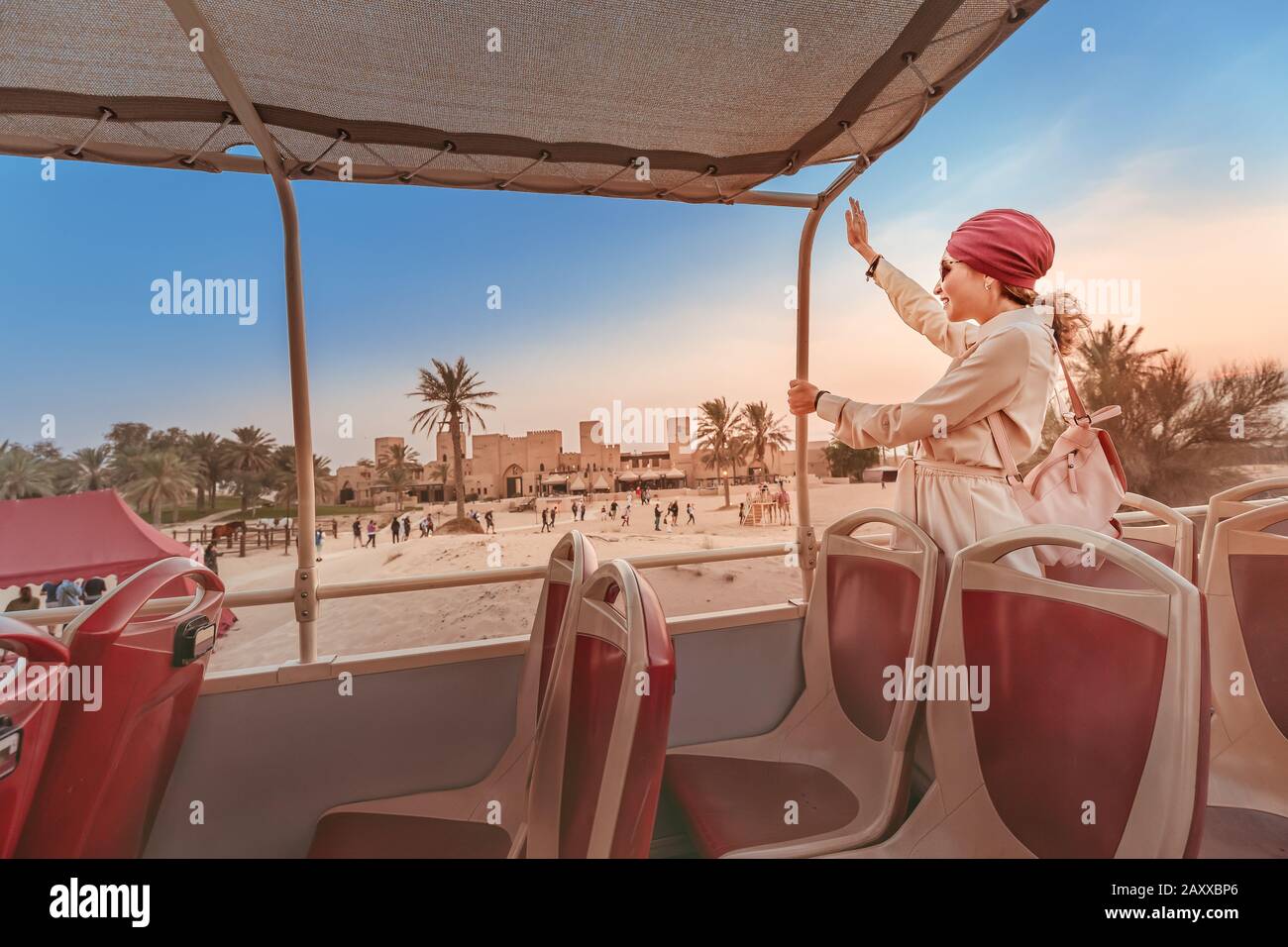 A happy girl in an Indian headdress travels on the roof of a bus in a natural and historical Park. Desert Safari and adventure concept Stock Photo