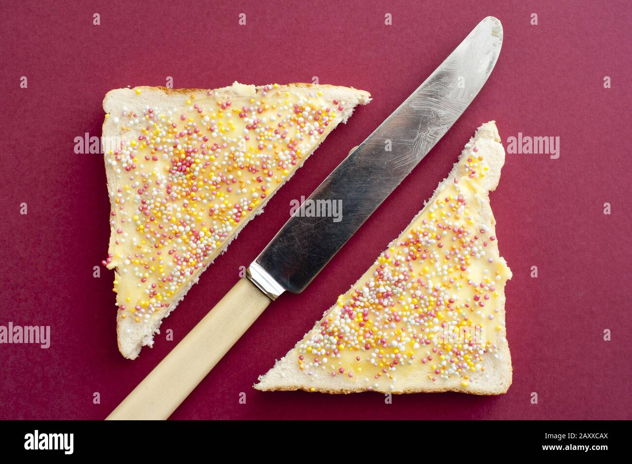 Single Butter Knife With White Handle In Between Slices Of Fairy Bread Covered With Butter And Candy Sprinkling Over Red Background Stock Photo Alamy