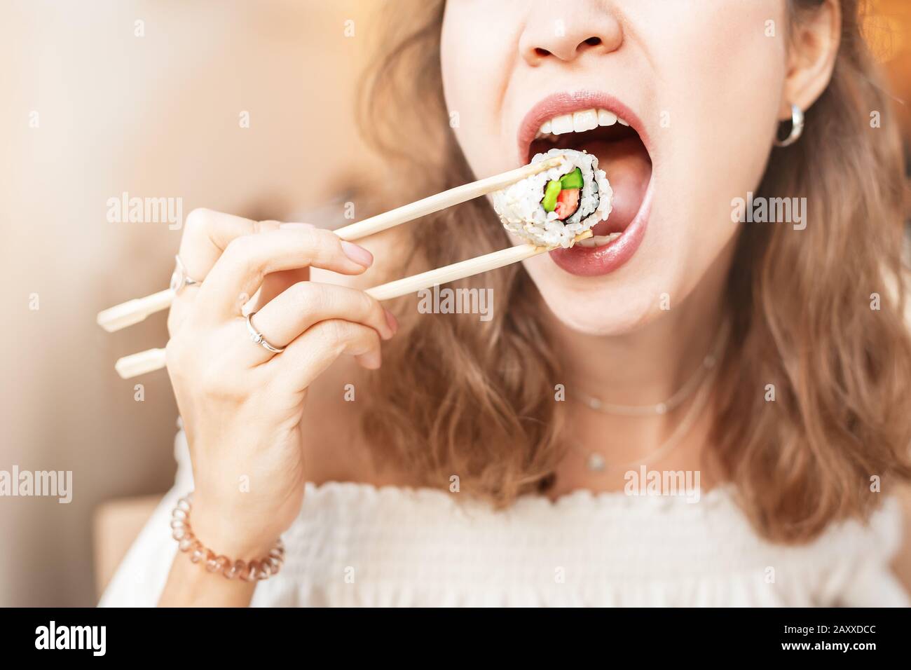 Girl eating sushi with chopsticks while having Bento lunch in the food court Stock Photo