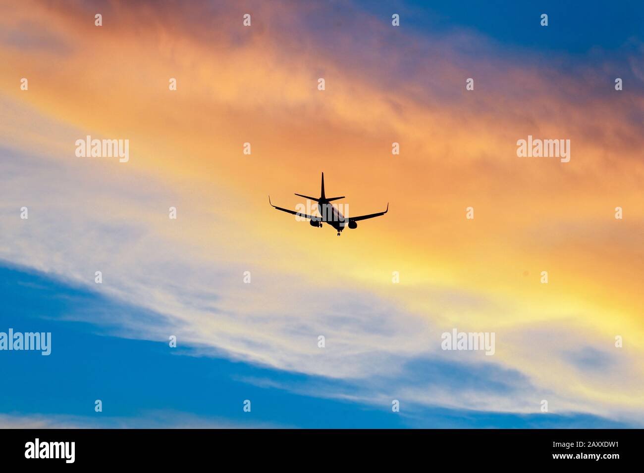 Commercial jet descending at sunset. Stock Photo