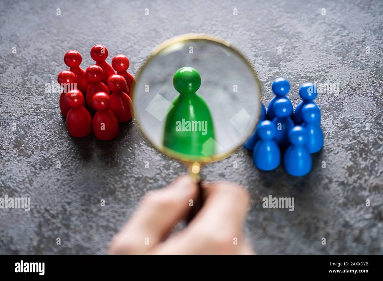 A Male Looking At Colorful Pawns With Magnifying Glass On The Desk Stock Photo