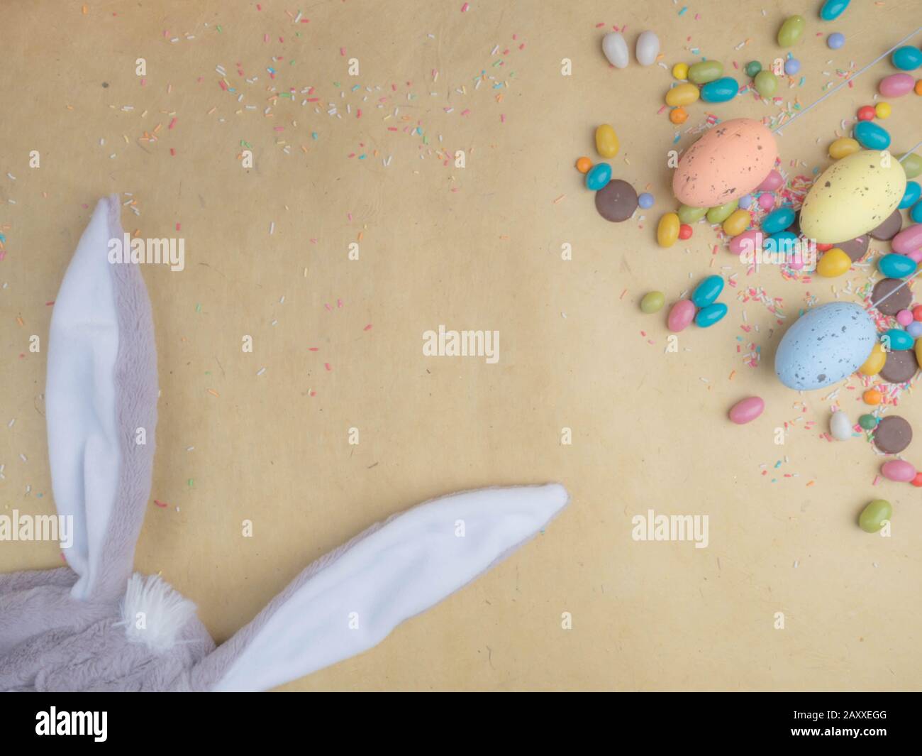 Cute creative composition with multi colored easter eggs, colorful sweets, and bunny ears. Easter and Springtime concept Stock Photo