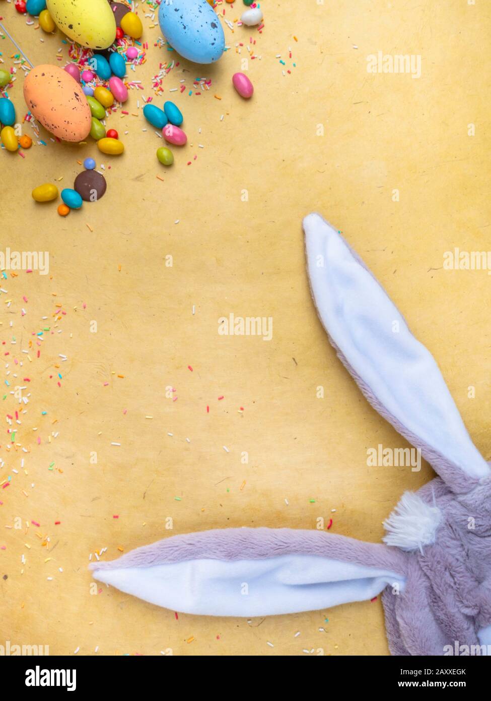 Cute creative composition with multi colored easter eggs, colorful sweets, and bunny ears. Easter and Springtime concept Stock Photo