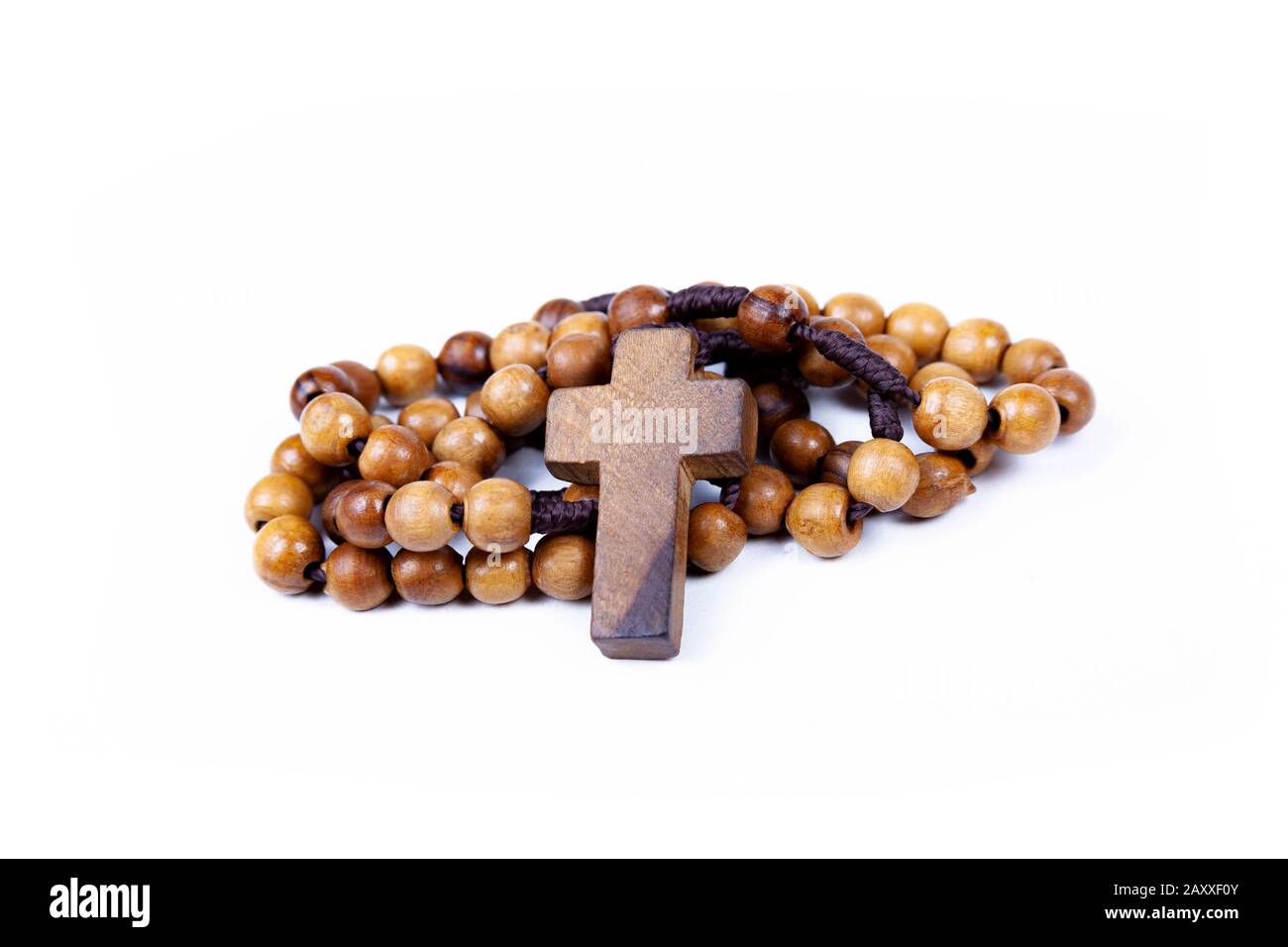Brown wooden christian rosary curled up, christianity religious symbols isolated on white. Cross symbol in the middle. Chaplet of Divine Mercy prayer Stock Photo