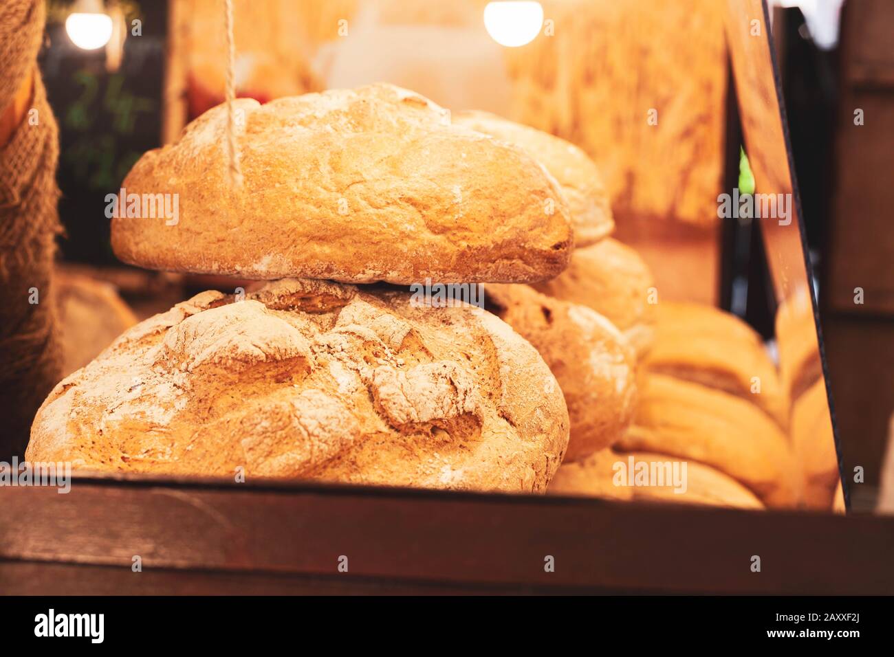Freshly baked big crusty round bread loafs with flour stacked on top of each other in a bakery / market stall shop surroundings. Warm colors, light Stock Photo