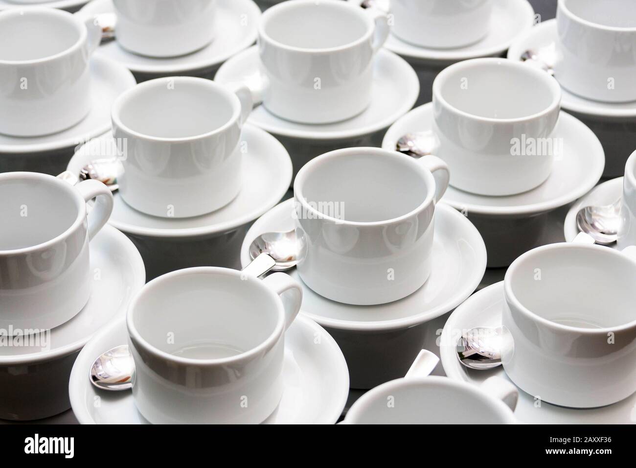 Many empty white tea cups abstract food industry background texture, repetitive pattern Cups stacked with spoons wallpaper White dishes, catering Stock Photo