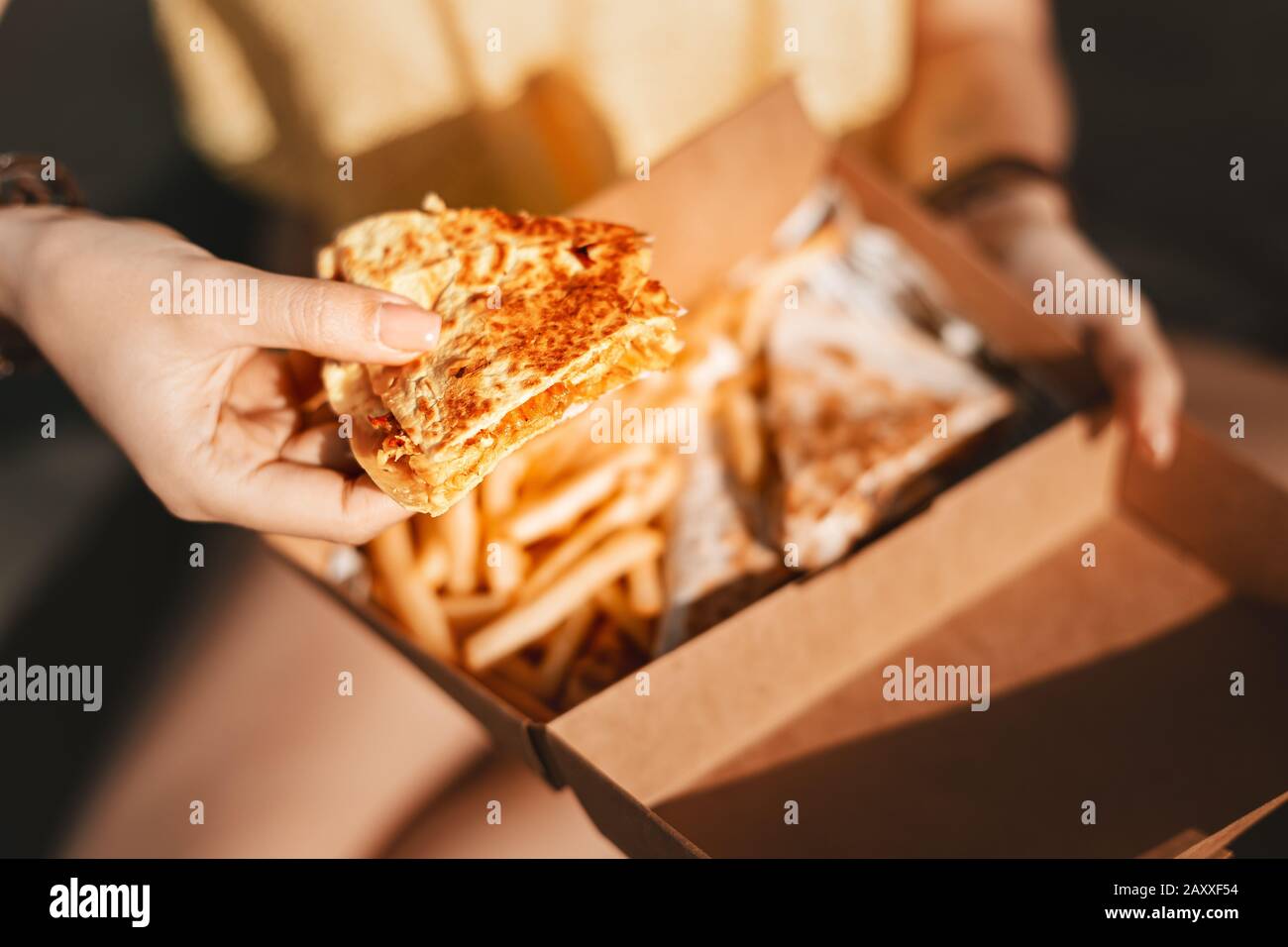 Happy girl eating Mexican fast food quesadilla. Streetfood and junk food with high calories and fat Stock Photo