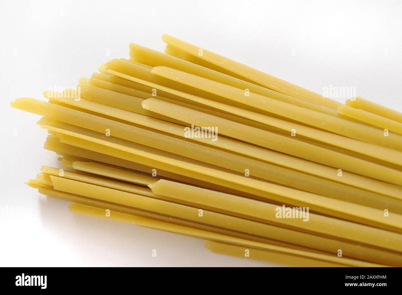 Bundle of traditional dried Italian tagliatelli pasta for use in Mediterranean cuisine on a white background with copyspace Stock Photo