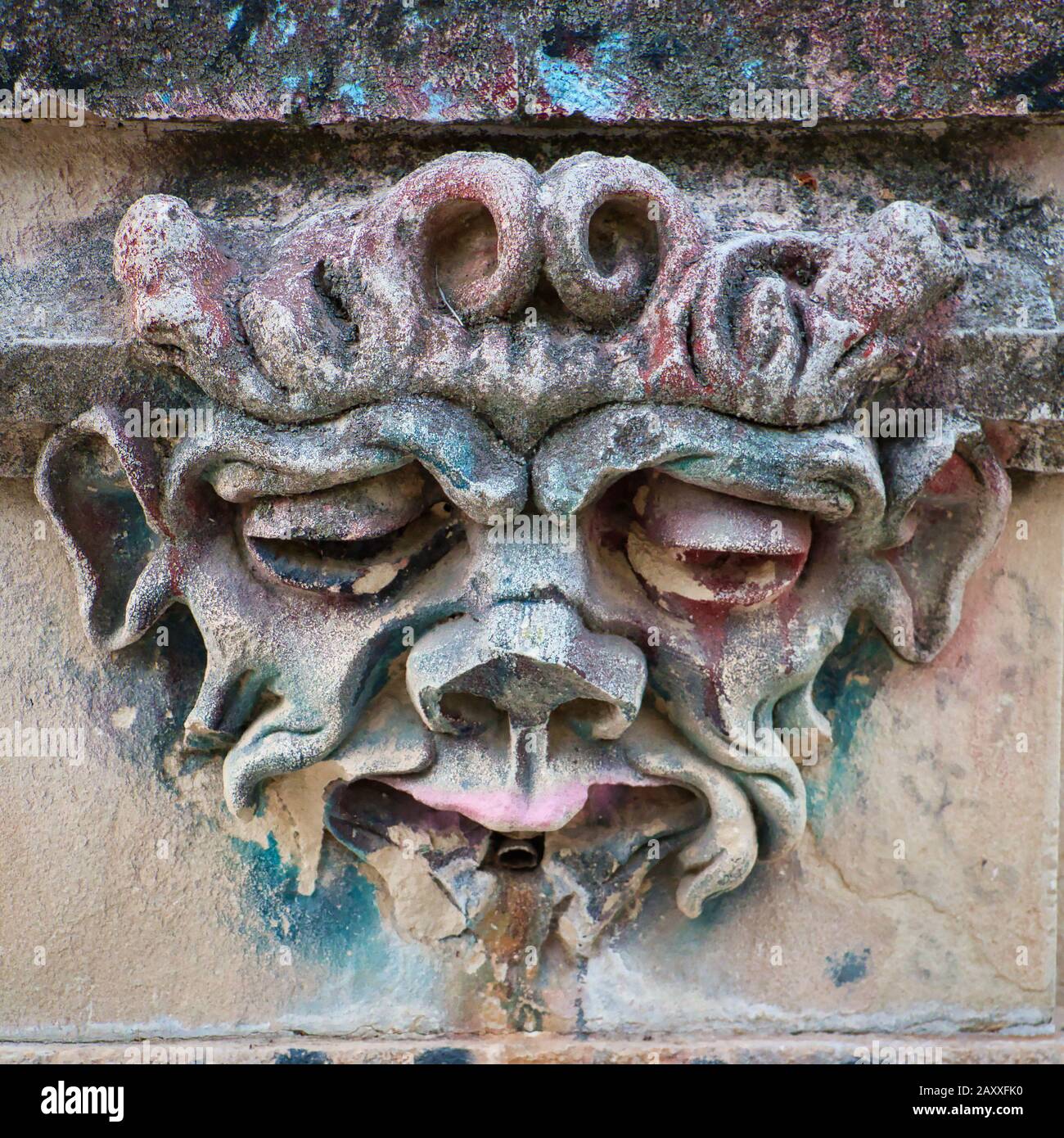 Stone front of a public fountain in a park in Cuenca, (Spain), where the water pipe is located at the mouth of a monstrous face Stock Photo