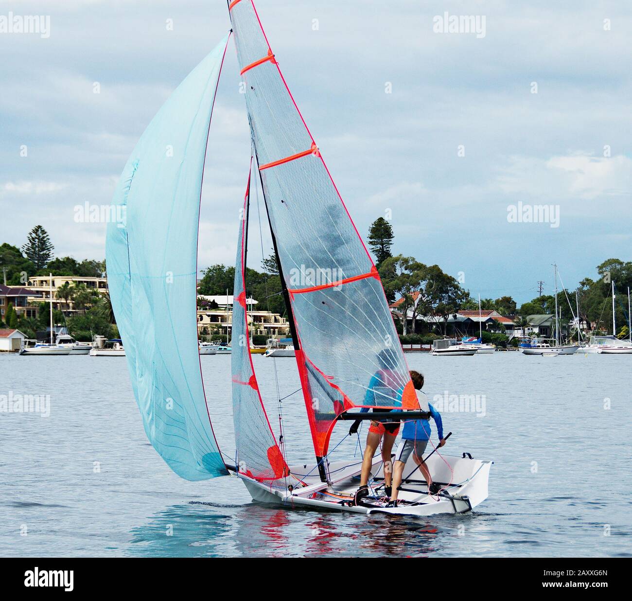 Two young boys sailing a 29er class dinghy with a clear mylar mainsail in competition. Teamwork by junior sailors racing on saltwater Lake Macquarie. Stock Photo