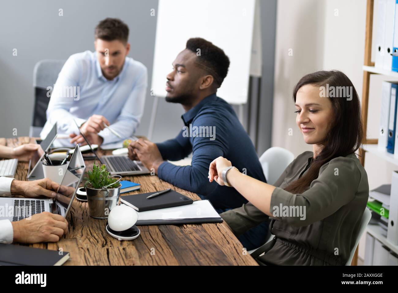 Woman Checking Time While Sitting In A Boring Long Meeting Stock Photo