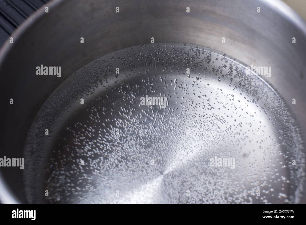 Overhead view of water beginning to boil in a stainless steel quart