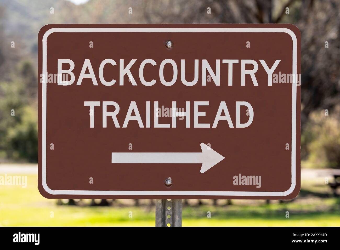 Backcountry trailhead sign pointing towards hiking trail in wilderness nature park. Stock Photo