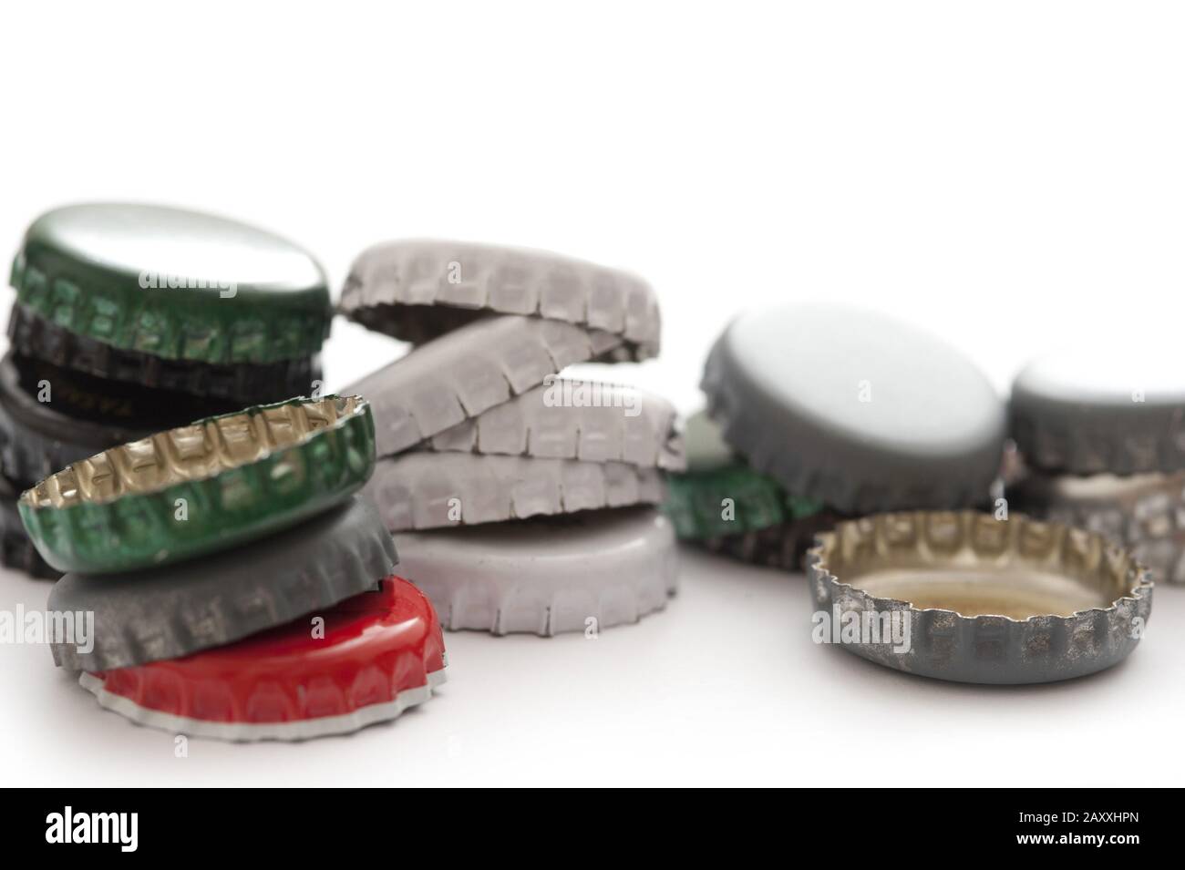 Pile of assorted metal bottle tops from bottled drinks in different colours, close up view on white with copyspace Stock Photo