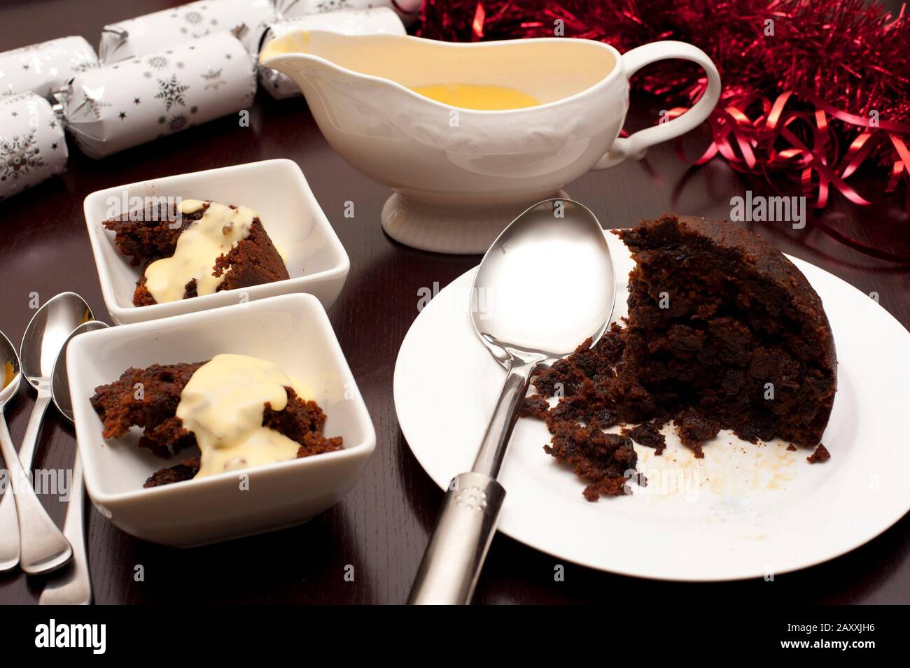 Delicious fruity Christmas pudding with brandy cream sauce served in dishes  on a decorative Christmas table for a seasonal Xmas celebration Stock Photo  - Alamy