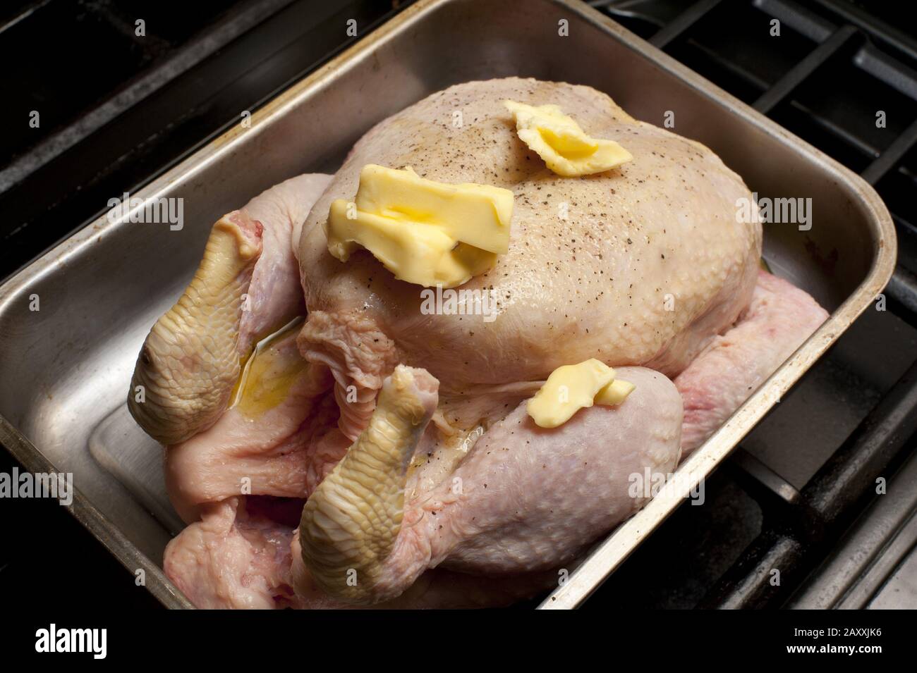 Fresh whole raw chicken seasoned with spices and daubed with butter