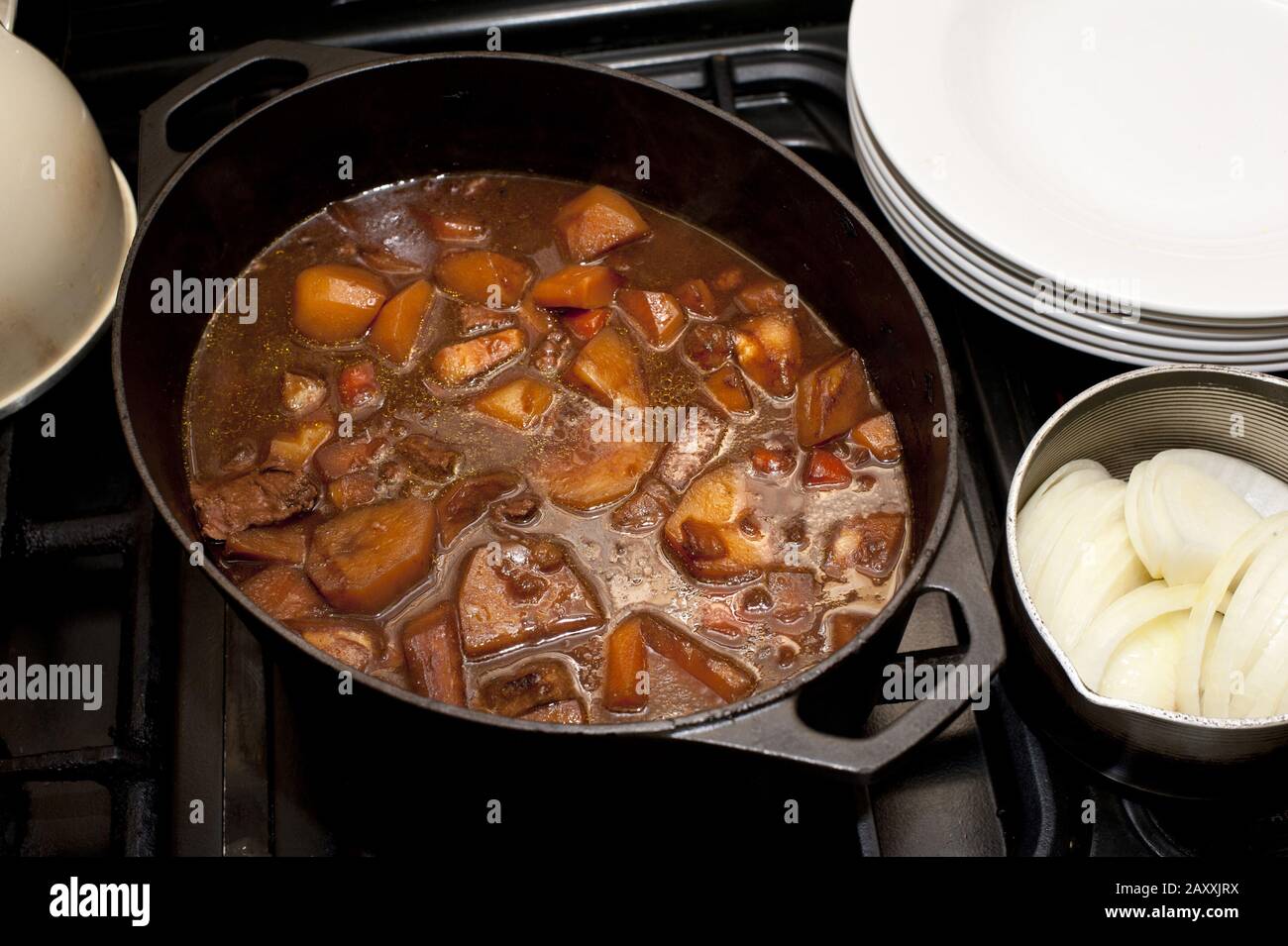 Delicious hot soup with potatoes, meat, different vegetables in saucepan on stove. From above Stock Photo