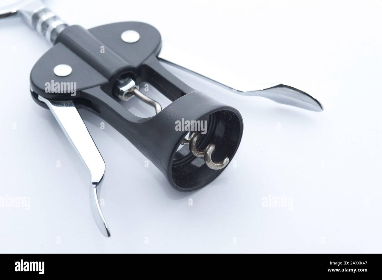 Lever style wine bottle opener with corkscrew lying on a white