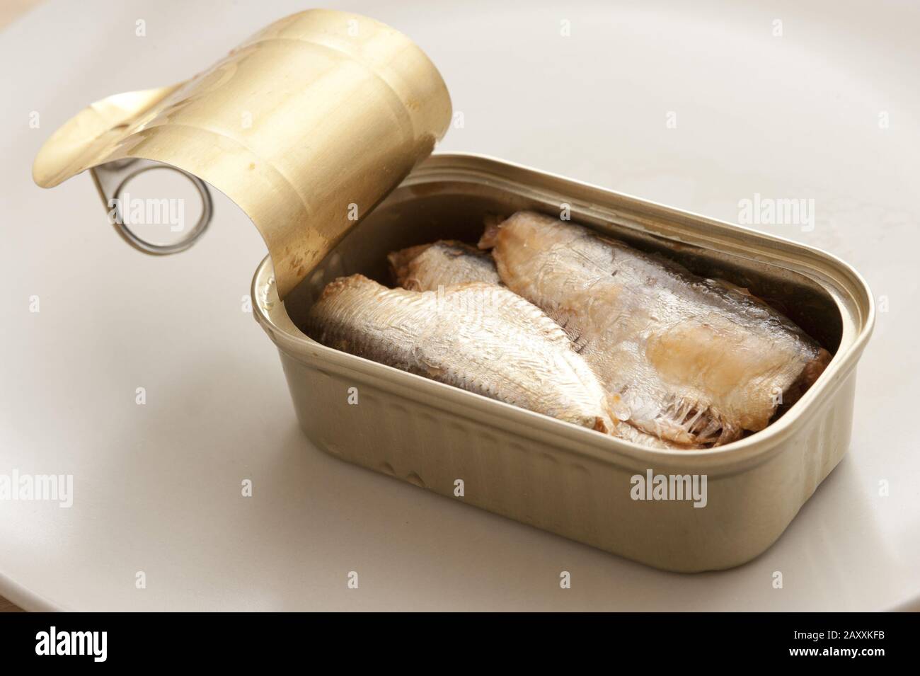 Single open aluminum can of drained sardines ready to eat over white