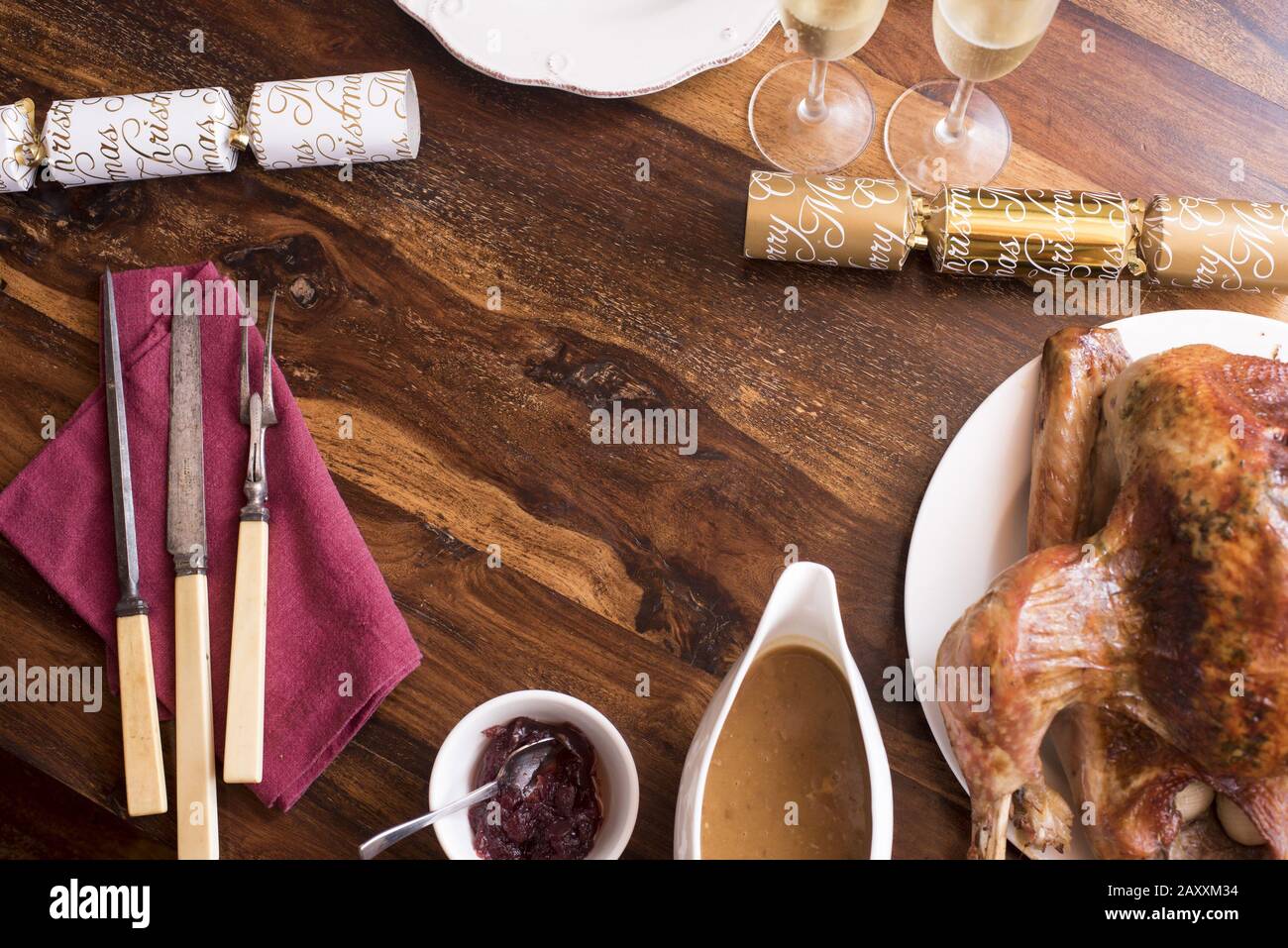 Top down Christmas table still life arranged as a frame with a roast turkey, gravy, cranberry sauce, crackers champagne, and utensils around copy spac Stock Photo