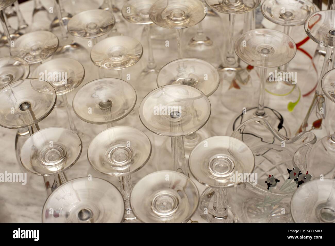 Variety of upended clean glassware with assorted shapes of wineglasses and glasses on a white table in a bar or restaurant Stock Photo